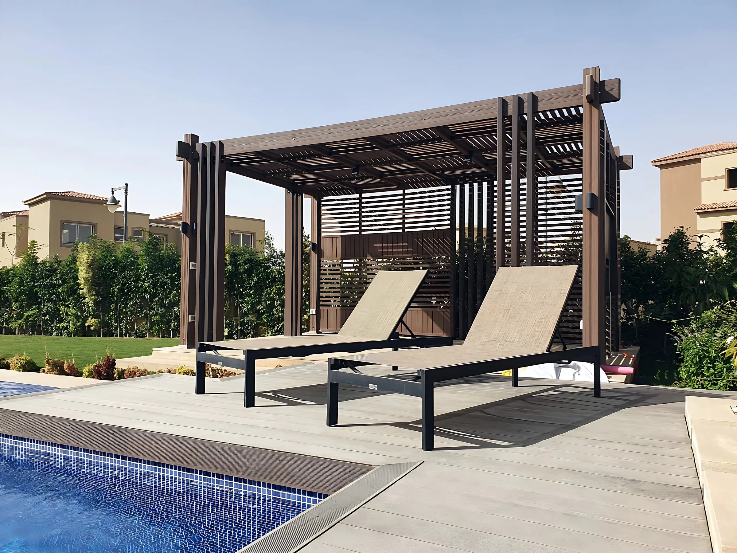 Wood-effect pergola beside a pool, with sun loungers