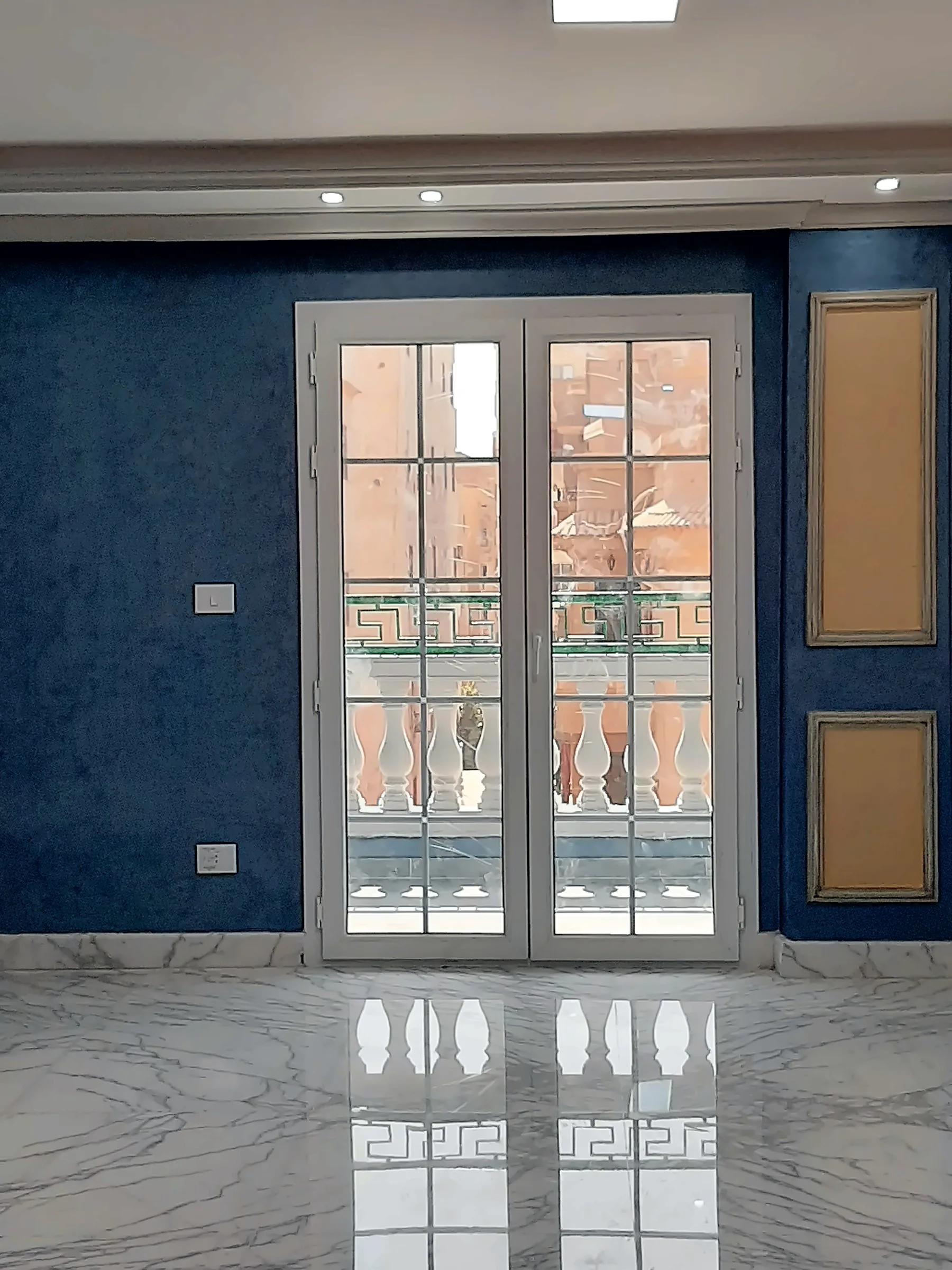 White French doors opening onto a balcony, in a room with blue walls and a marble floor